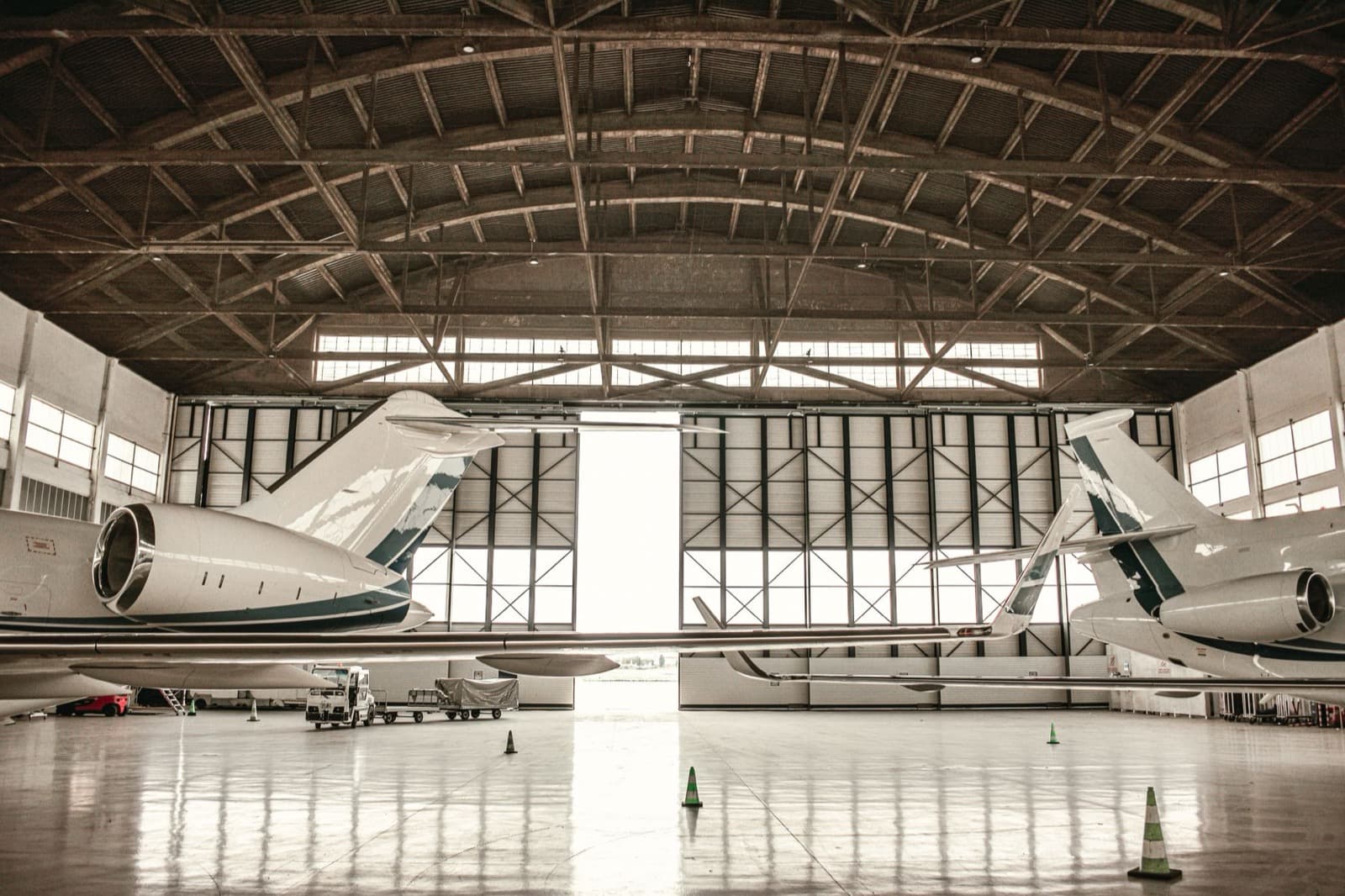 Two unmarked business jets facing each other inside an open hangar.